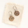 The bronze wanderer coin earrings styled on tan linen