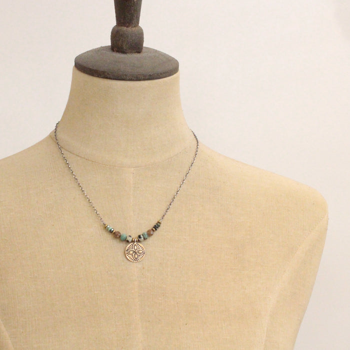 A mannequin wearing the bronze wanderer coin lona necklace