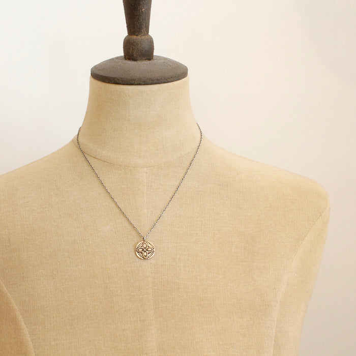 A mannequin wearing the bronze wanderer coin necklace