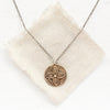 The bronze wanderer coin necklace styled on tan linen