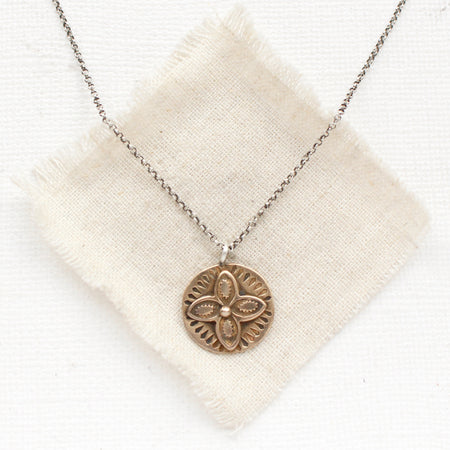 The bronze wanderer coin necklace styled on tan linen
