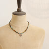 A mannequin wearing the bronze wanderer coin turquoise ombre necklace 