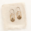 The bronze wanderer hoop earrings styled on tan linen