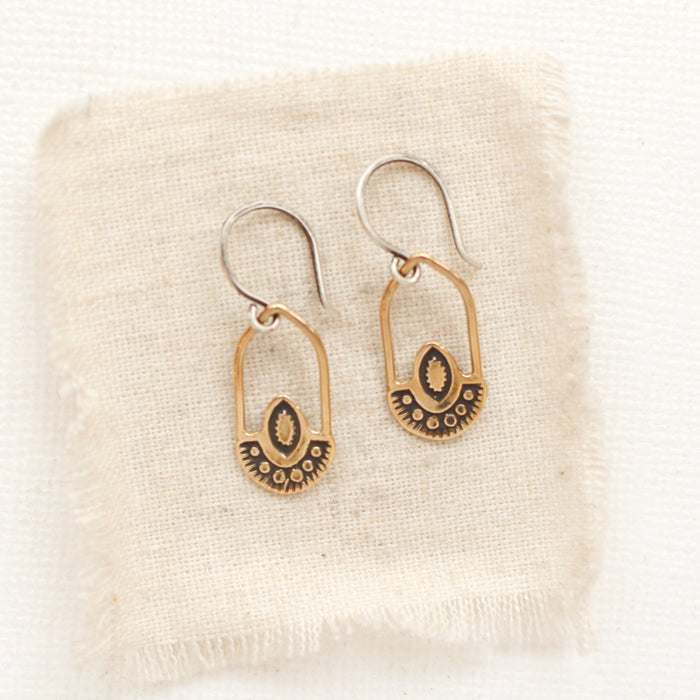 The bronze wanderer hoop earrings styled on tan linen