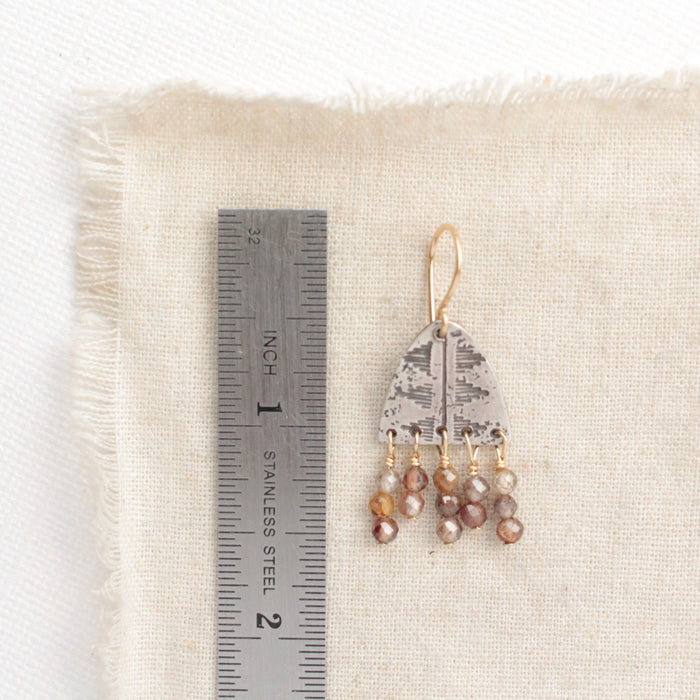 A brown zircon pakal fringe earring next to a ruler for size reference