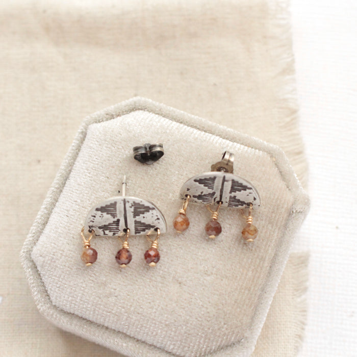 The brown zircon pakal arch post earrings styled on a velvet box to show the butterfly earbacks