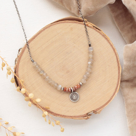The talara sun zaria necklace styled on wood with tan velvet and dried grass