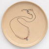 The talara sun zaria necklace styled on a tan plate to show the adjustable lobster clasp closure