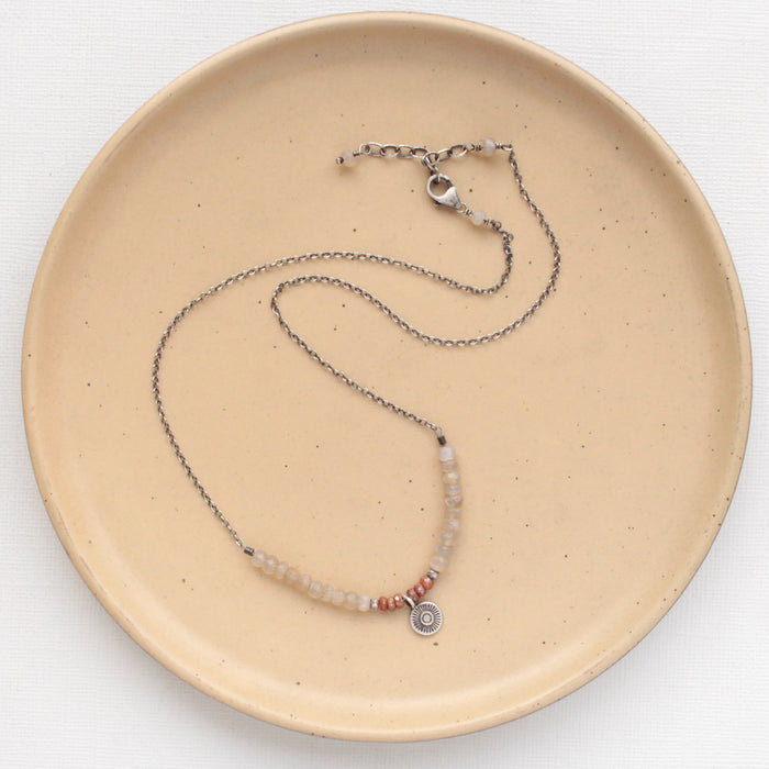The talara sun zaria necklace styled on a tan plate to show the adjustable lobster clasp closure