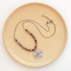 The brown zircon wanderer medallion necklace styled on a tan plate to show the adjustable lobster clasp closure