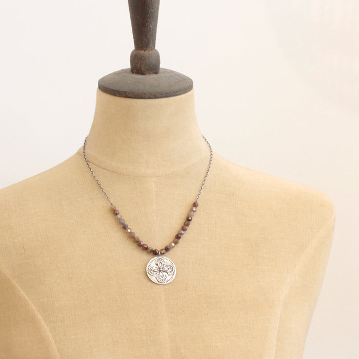 A mannequin wearing the brown zircon wanderer medallion necklace