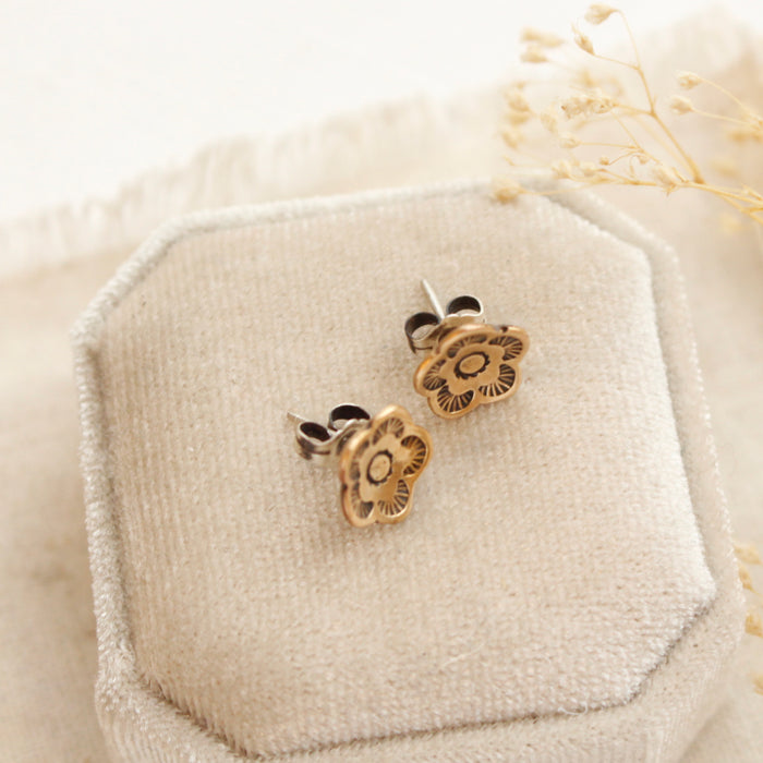 The bronze mini cactus flower post earrings styled on a velvet box to show the butterfly earbacks