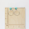 The carved turquoise flower post hoop earrings on a wooden ruler for size reference
