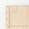 The chalcedony drop earrings styled on a wooden ruler for size reference