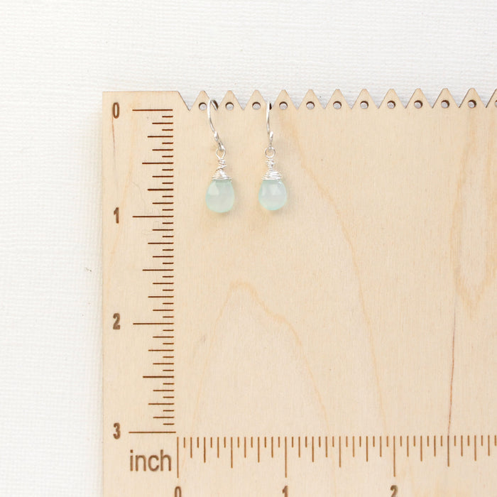 The chalcedony drop earrings styled on a wooden ruler for size reference