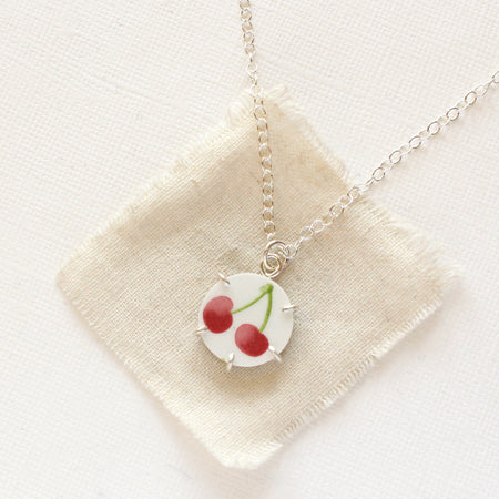 The twin cherry vintage plate necklace styled on tan linen