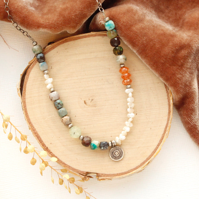 The talara sun mesa necklace styled on wood with orange velvet and dried grass