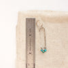 A chrysocolla wrapped long hoop earring next to a ruler for size reference