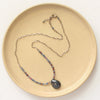 The cleo sapphire necklace styled on a tan plate to show the adjustable lobster clasp clousure