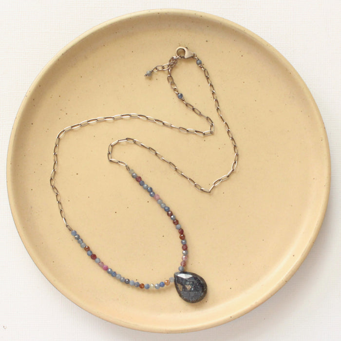 The cleo sapphire necklace styled on a tan plate to show the adjustable lobster clasp clousure