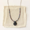 The cleo sapphire necklace styled on tan linen