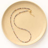 The dainty sapphire necklace styled on a tan plate to show the adjustable lobster clasp closure
