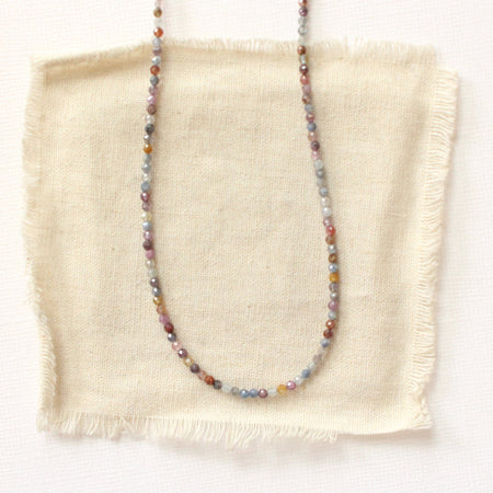 The dainty sapphire necklace styled on tan linen