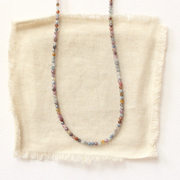 The dainty sapphire necklace styled on tan linen