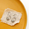 The dalmatian jasper la cloche earrings styled on a yellow plate with tan linen