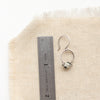 A dalmatian jasper la cloche earring next to a ruler for size reference