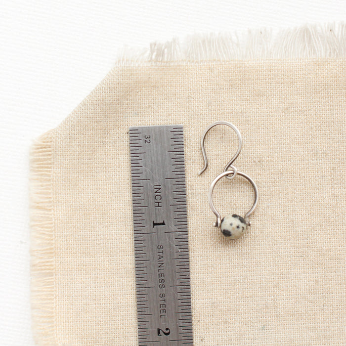A dalmatian jasper la cloche earring next to a ruler for size reference