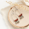 The moab arch earrings styled on wood with linen and dried grass