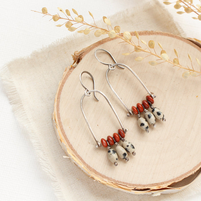 The moab arch earrings styled on wood with linen and dried grass