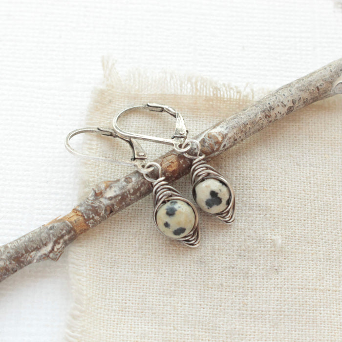 The perfect wrapped dalmatian jasper earrings styled on tan linen with a wooden stick