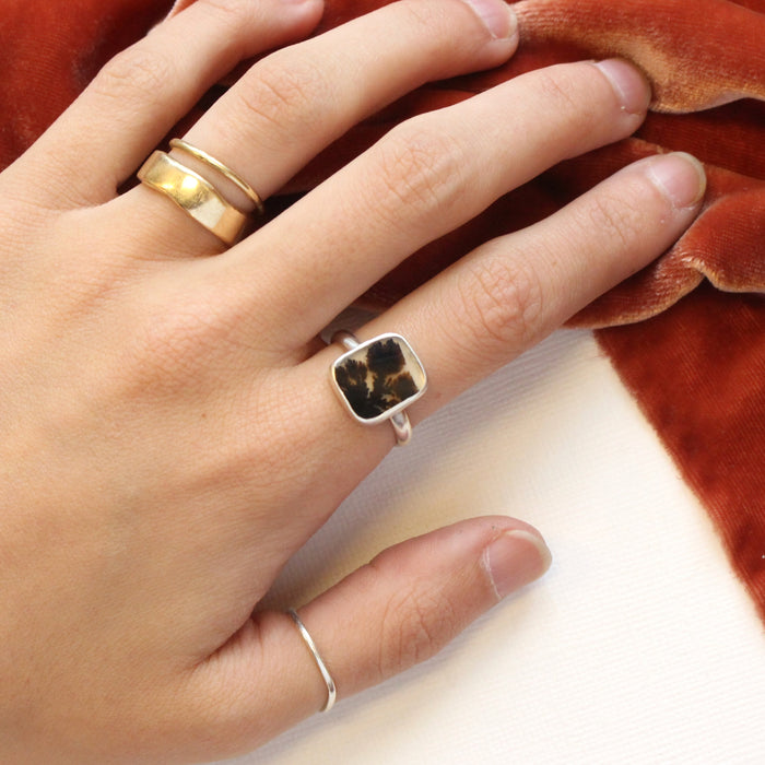The dendritic agate ring being worn on a hand