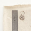 An embossed siena disc earring next to a ruler for size reference
