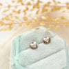 The silver heart post earrings styled on a blue velvet box with linen and dried grass