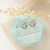 The embossed heart post earrings styled on a blue velvet box with linen and dried grass