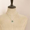A mannequin wearing the emerald drop gold necklace