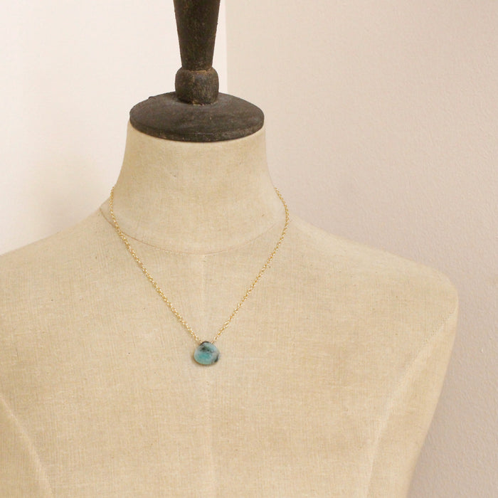 A mannequin wearing the emerald drop gold necklace