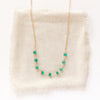 The emerald collar necklace styled on tan linen