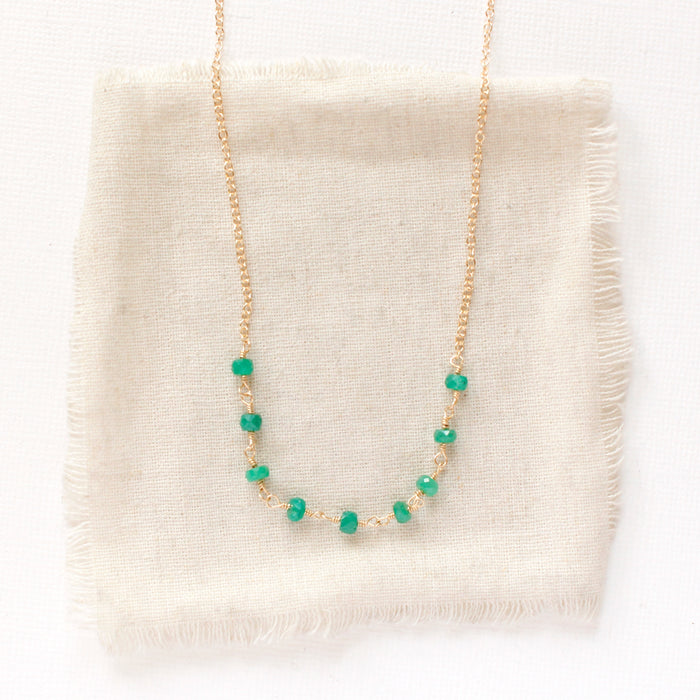 The emerald collar necklace styled on tan linen