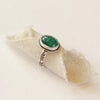 The emerald ring styled on tan linen to show the stamped silver band