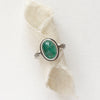 The emerald and stamped rays ring styled on rolled tan linen