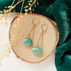 The emerald swing earrings styled on wood with green velvet and dried grass