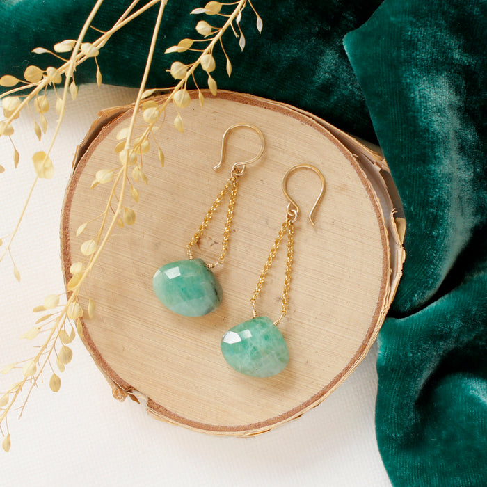 The emerald swing earrings styled on wood with green velvet and dried grass