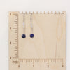 The opal and lapis earrings on a wooden ruler for size reference