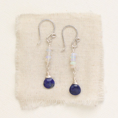 The opal and lapis drop earrings styled on tan linen