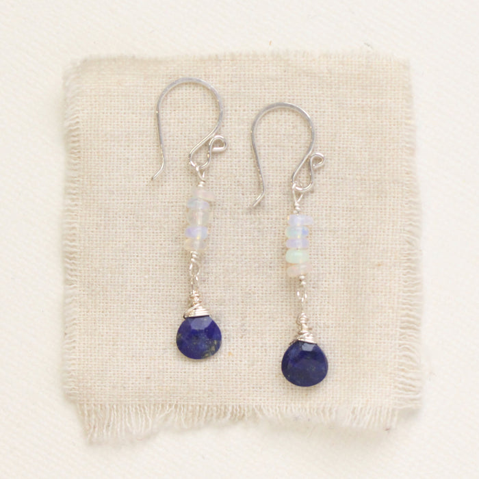 The opal and lapis drop earrings styled on tan linen