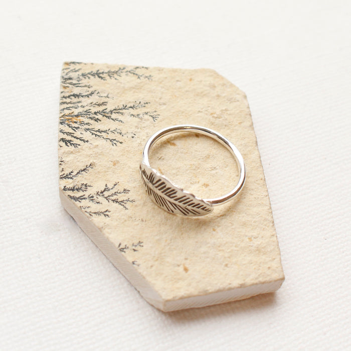 The feather embrace ring styled on a tan stone to show the thin band